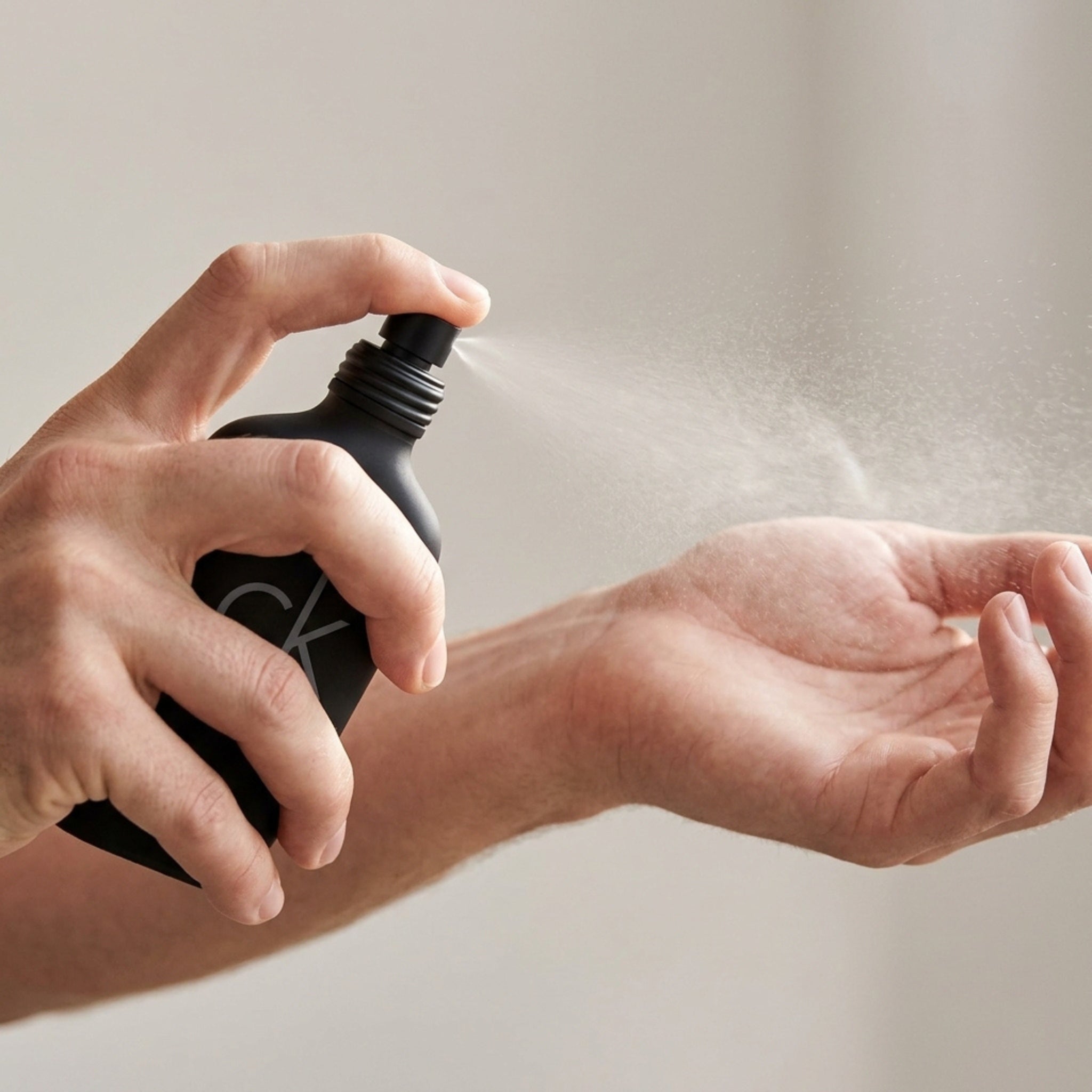 Spraying Calvin Klein CK Be perfume on wrist for better scent projection