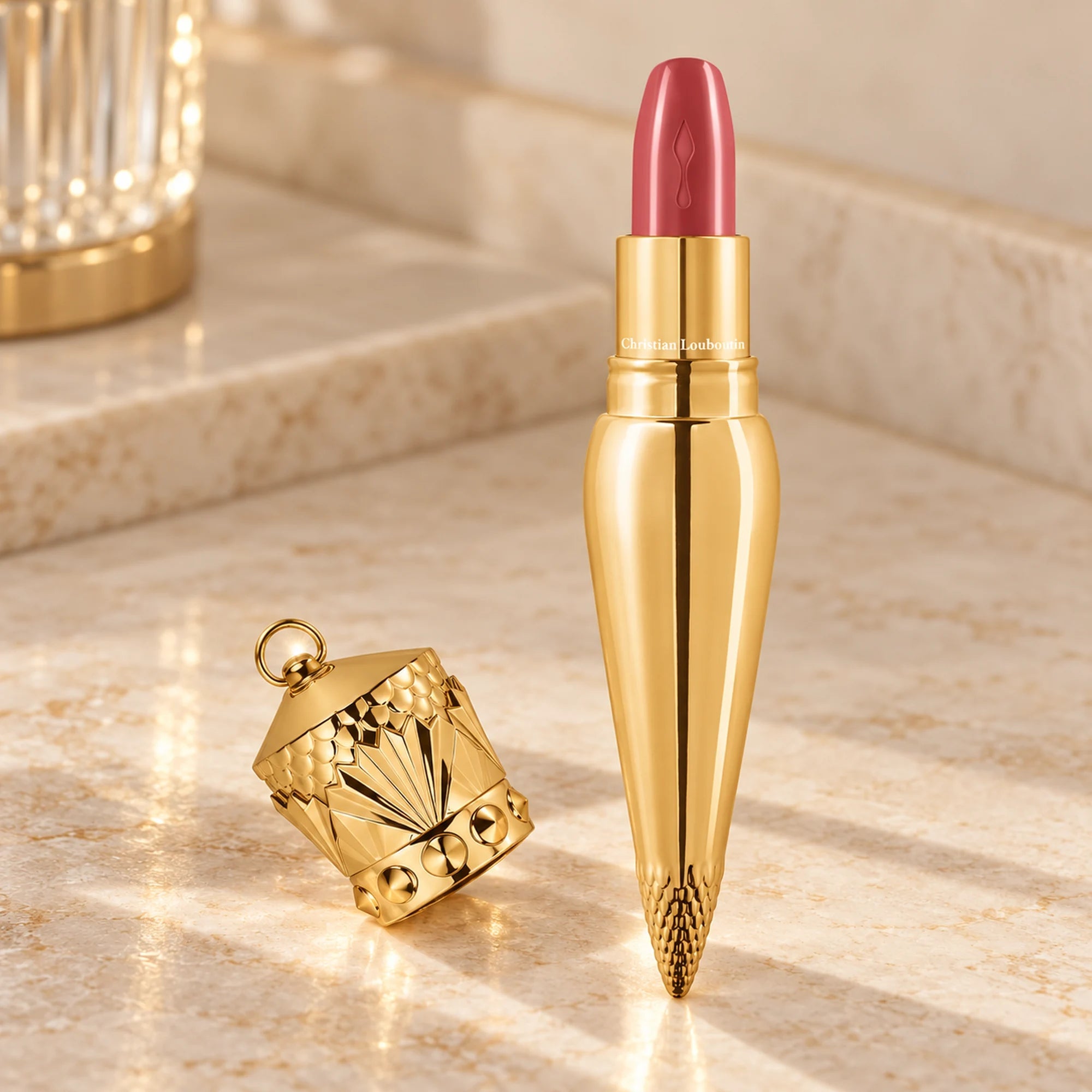 One Christian Louboutin Belly Bloom 011 lipstick with crown cap beside it on a cream vanity