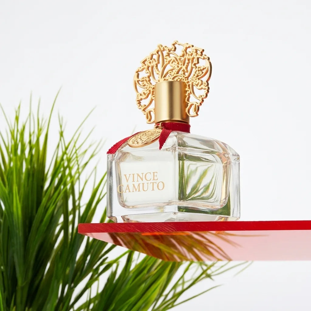 Vince Camuto perfume bottle with decorative gold cap against a pink and orange background